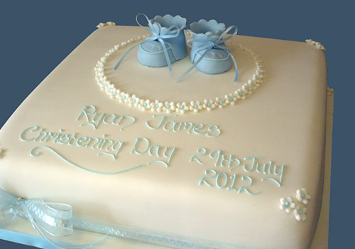 A Christening Cake with some little blue boots on the top
